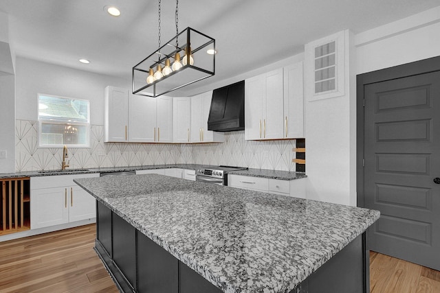 262 N 17th St, Columbus, OH 43203 - kitchen with stainless steel electric stove, a center island, premium range hood, sink, and white cabinetry