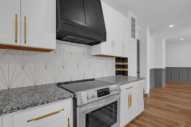 262 N 17th St, Columbus, OH 43203 - kitchen featuring dark stone countertops, light hardwood / wood-style floors, premium range hood, stainless steel electric range oven, and white cabinets