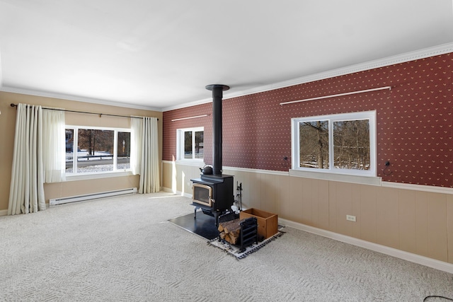 unfurnished living room with a wood stove, a baseboard heating unit, crown molding, and carpet flooring