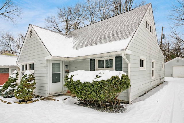 view of snow covered exterior featuring a garage and an outbuilding