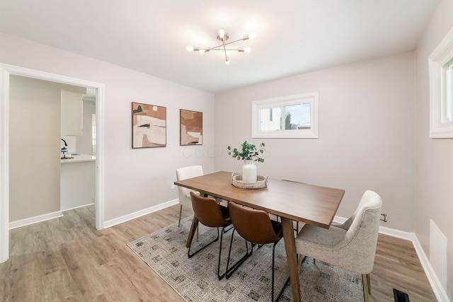 dining space featuring light hardwood / wood-style floors and a notable chandelier