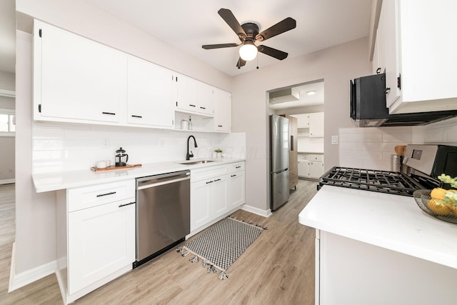 kitchen with light hardwood / wood-style flooring, decorative backsplash, white cabinets, appliances with stainless steel finishes, and sink