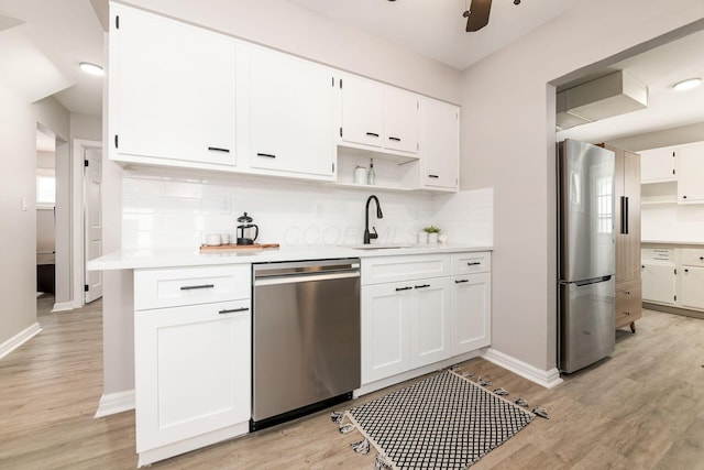 kitchen featuring sink, white cabinetry, light hardwood / wood-style flooring, backsplash, and appliances with stainless steel finishes