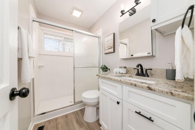 bathroom featuring toilet, vanity, hardwood / wood-style flooring, and walk in shower