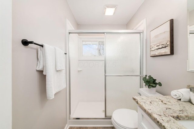 bathroom with toilet, a shower with shower door, and vanity