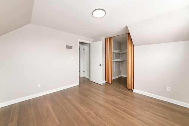 unfurnished bedroom featuring hardwood / wood-style floors, a closet, and vaulted ceiling