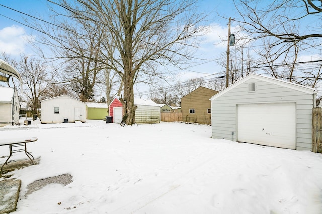 snowy yard featuring a garage and a shed