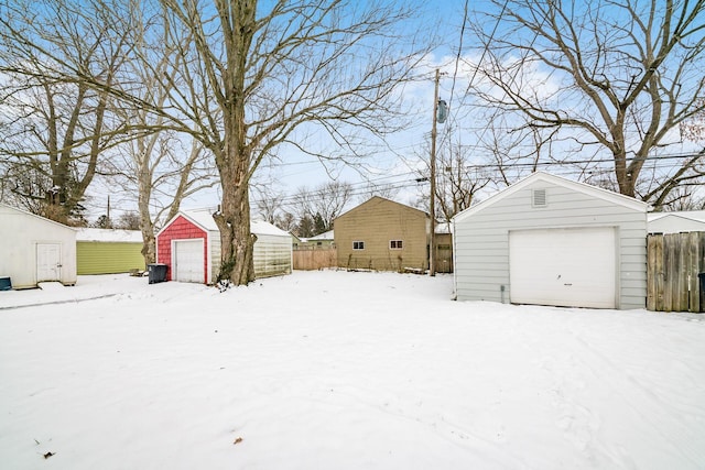 snowy yard with a garage and an outdoor structure