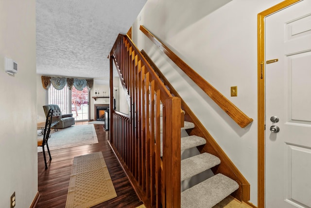 stairs with a textured ceiling and hardwood / wood-style flooring