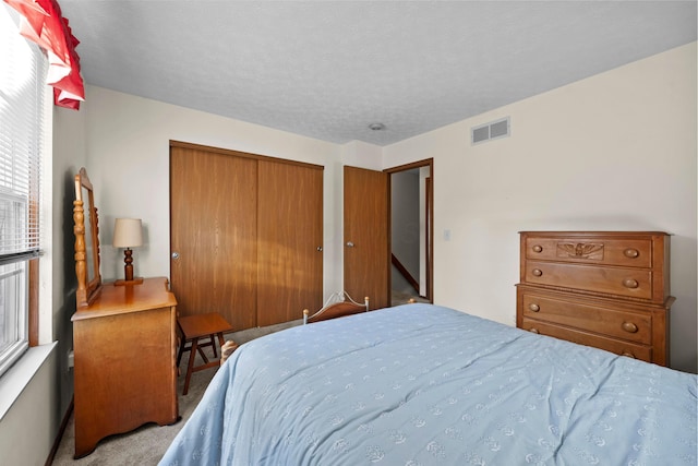 carpeted bedroom featuring a closet and a textured ceiling