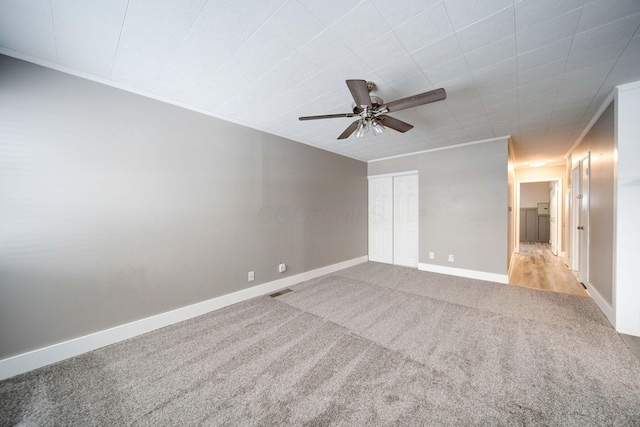 carpeted empty room with ceiling fan and ornamental molding