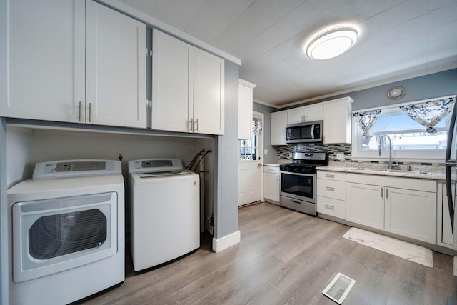 laundry area featuring sink, crown molding, independent washer and dryer, and light wood-type flooring