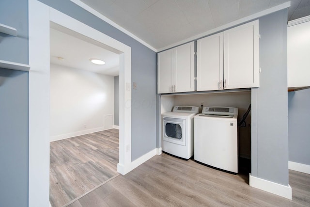 laundry room with light wood-type flooring, washer and dryer, ornamental molding, and cabinets