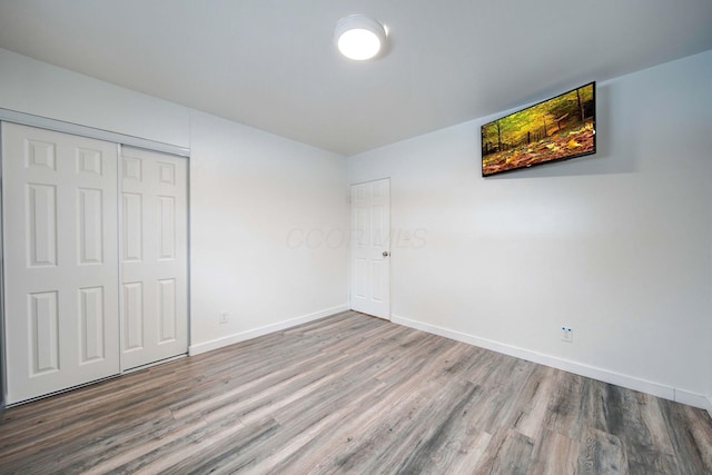 unfurnished bedroom featuring wood-type flooring and a closet