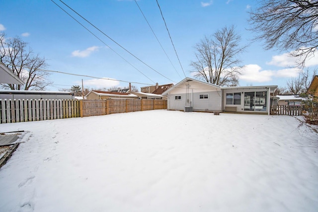 snowy yard featuring a sunroom