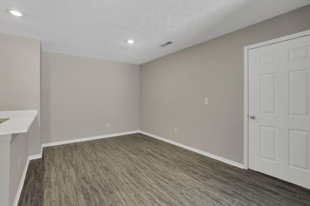 spare room with a textured ceiling and dark hardwood / wood-style flooring