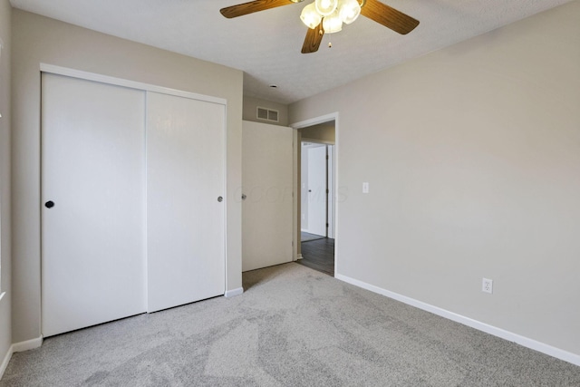 unfurnished bedroom with a textured ceiling, ceiling fan, a closet, and light colored carpet