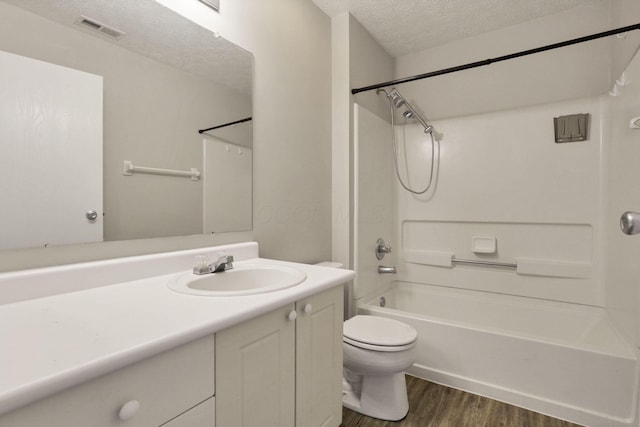 full bathroom with a textured ceiling, bathing tub / shower combination, wood-type flooring, vanity, and toilet