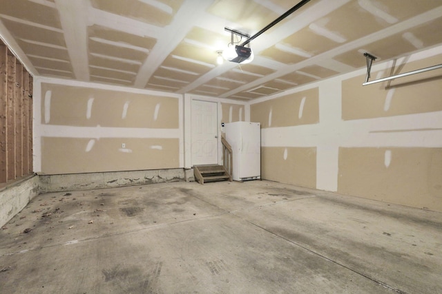 garage featuring white fridge and a garage door opener