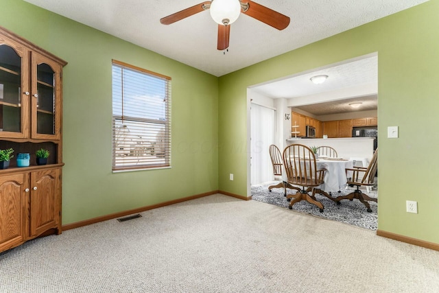 carpeted dining space featuring a textured ceiling and ceiling fan