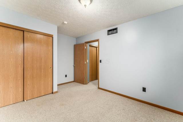 unfurnished bedroom featuring a closet, a textured ceiling, and light colored carpet