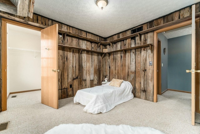 bedroom featuring a closet, wood walls, a textured ceiling, and carpet floors