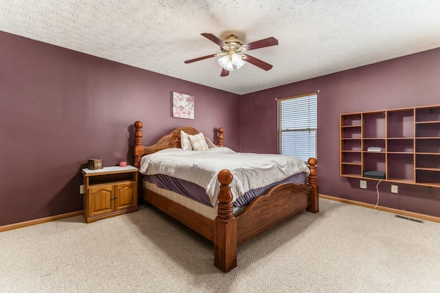 bedroom with a textured ceiling, ceiling fan, and light colored carpet