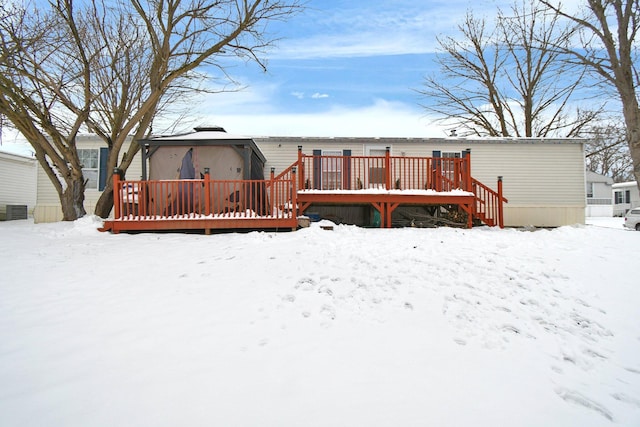 snow covered back of property with a deck