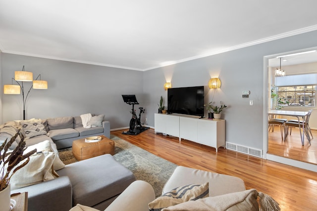 living room with an inviting chandelier, crown molding, and wood-type flooring