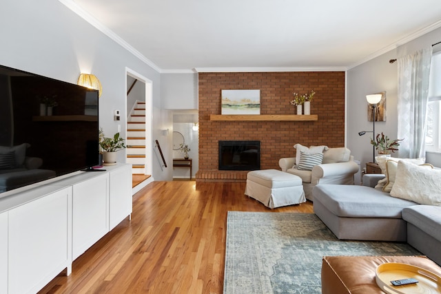 living room with light wood-type flooring, ornamental molding, and a fireplace