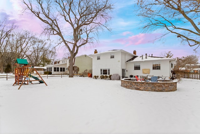 snow covered house with a playground