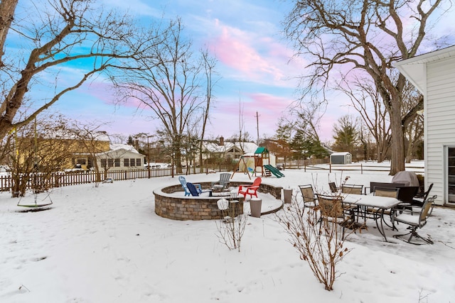 yard layered in snow featuring an outdoor fire pit and a playground