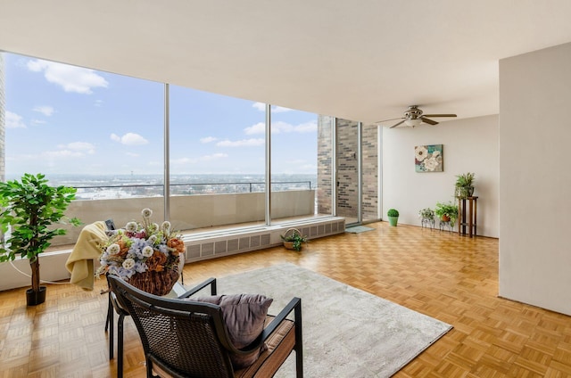 living room featuring radiator, ceiling fan, a water view, and light parquet flooring