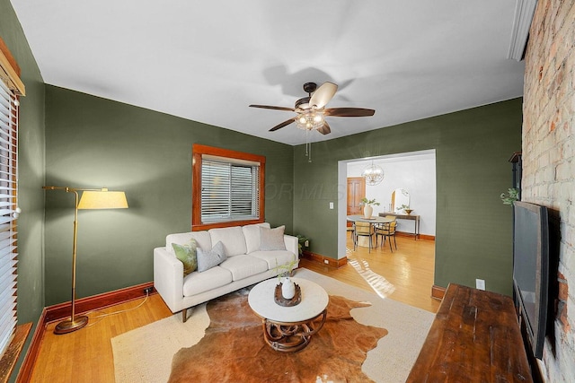 living room featuring ceiling fan with notable chandelier and hardwood / wood-style flooring