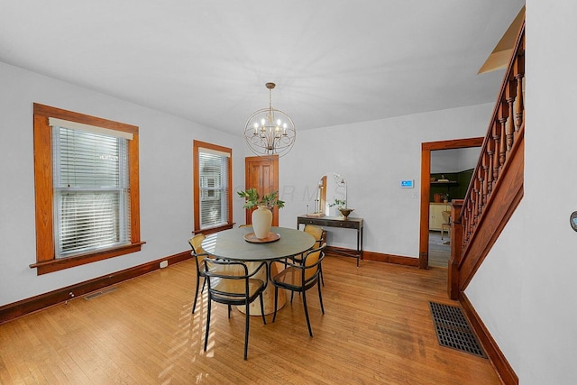 dining room with light wood-type flooring and a notable chandelier