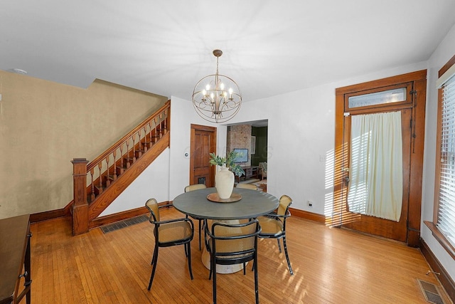 dining space with an inviting chandelier, a healthy amount of sunlight, and light hardwood / wood-style floors