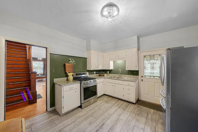 kitchen with sink, appliances with stainless steel finishes, light hardwood / wood-style floors, and white cabinetry