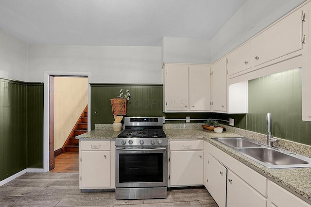 kitchen with sink, stainless steel gas range oven, and white cabinetry