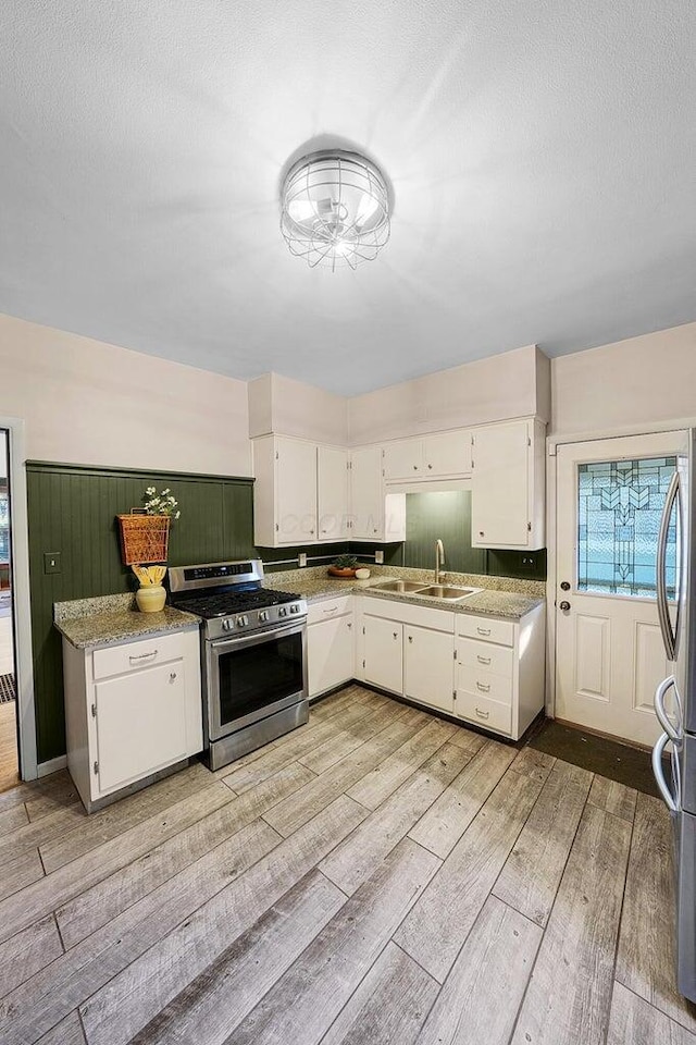 kitchen with sink, a textured ceiling, appliances with stainless steel finishes, and white cabinetry