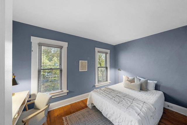 bedroom with multiple windows and dark wood-type flooring