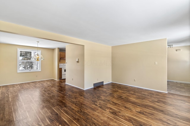 unfurnished room featuring dark hardwood / wood-style floors and a notable chandelier