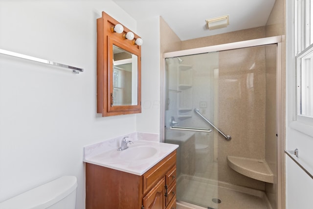 bathroom featuring toilet, vanity, and an enclosed shower