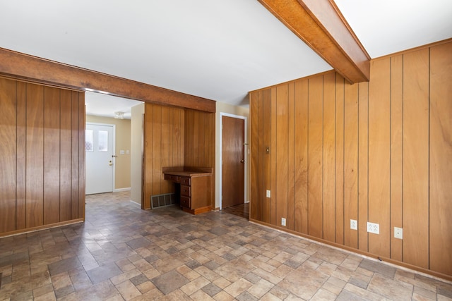 unfurnished living room with beamed ceiling and wooden walls