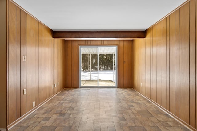 spare room with beam ceiling and wooden walls