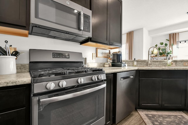 kitchen with sink, stainless steel appliances, light wood-type flooring, and dark brown cabinets