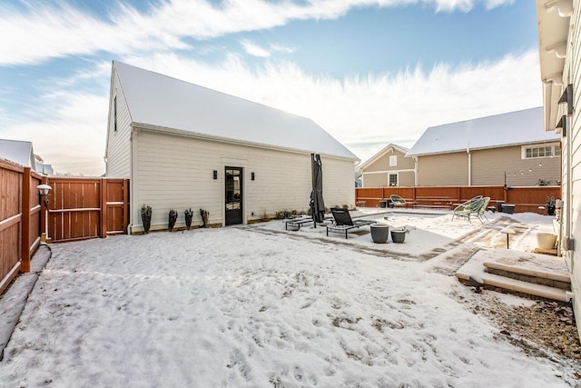 snow covered rear of property featuring an outdoor fire pit