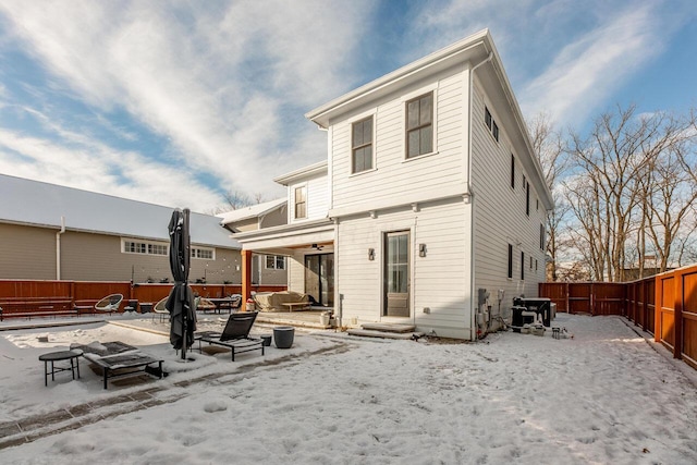 snow covered back of property with an outdoor fire pit