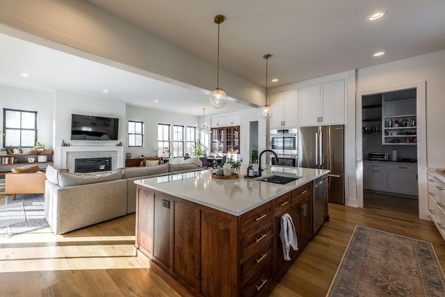 kitchen with white cabinetry, sink, a kitchen island with sink, and decorative light fixtures