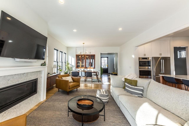 living room featuring a tile fireplace, a chandelier, and light wood-type flooring