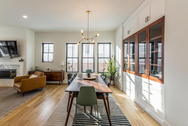 dining space with a premium fireplace, a chandelier, and light hardwood / wood-style flooring